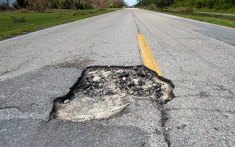 Large pothole on asphalt road requiring urgent UEP repair services.