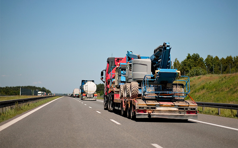Heavy machinery transported on highway for UEP road repair project.
