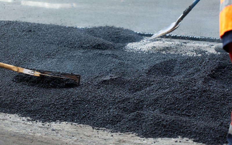 Laying cold mix asphalt for road repair.