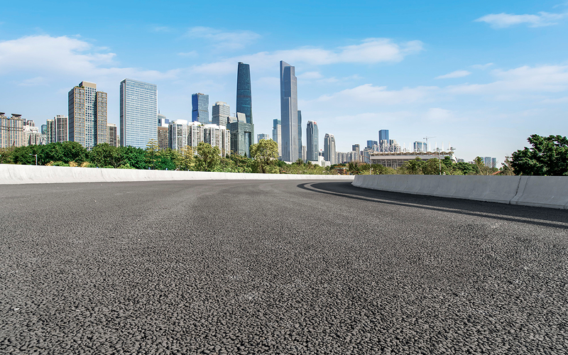 Smoothly paved highway road with a city skyline background.