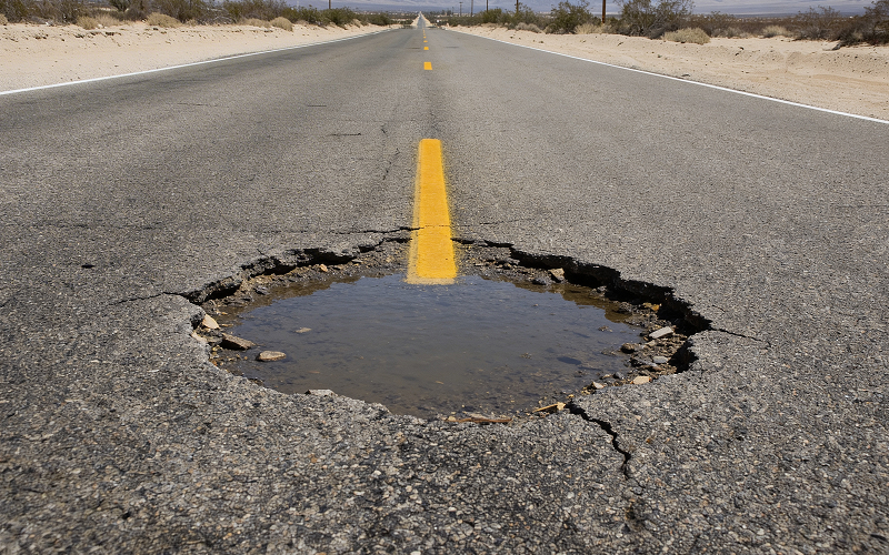 Large water-filled pothole needing corrective road maintenance works.