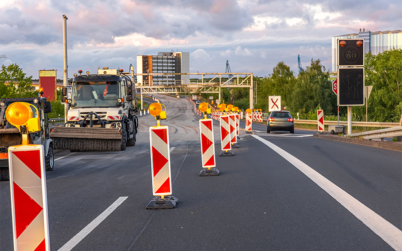 Urban roadwork with barriers, warning lights, and vehicles.