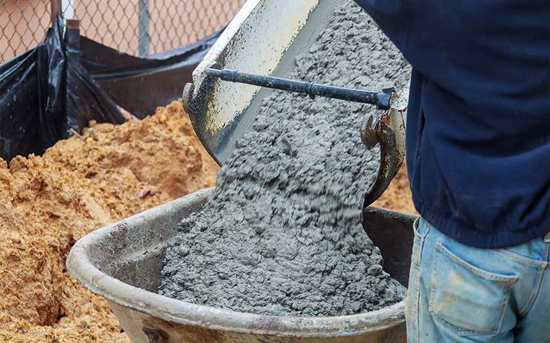 Concrete being poured from a chute into a wheelbarrow